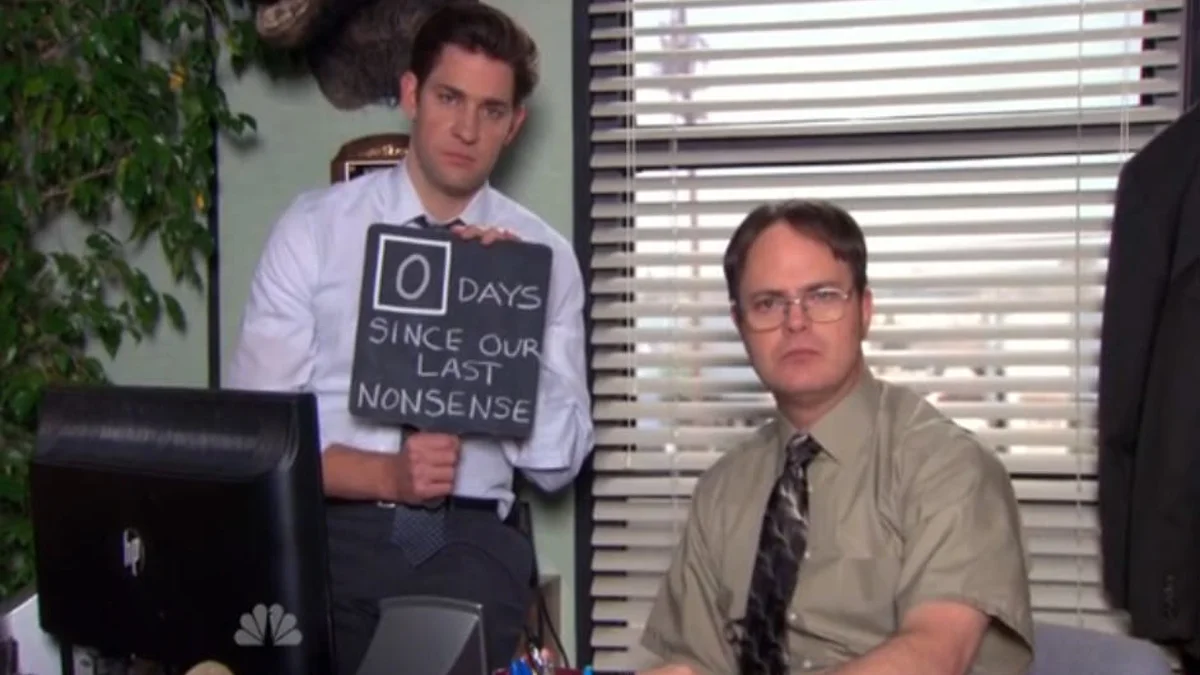 Jim from The Office holds a '0 Days Since Our Last Nonsense' chalkboard sign next to a stoic Dwight.