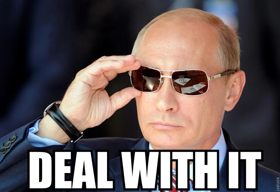 Political figure in formal attire adjusting dark sunglasses with white 'DEAL WITH IT' caption at bottom.
