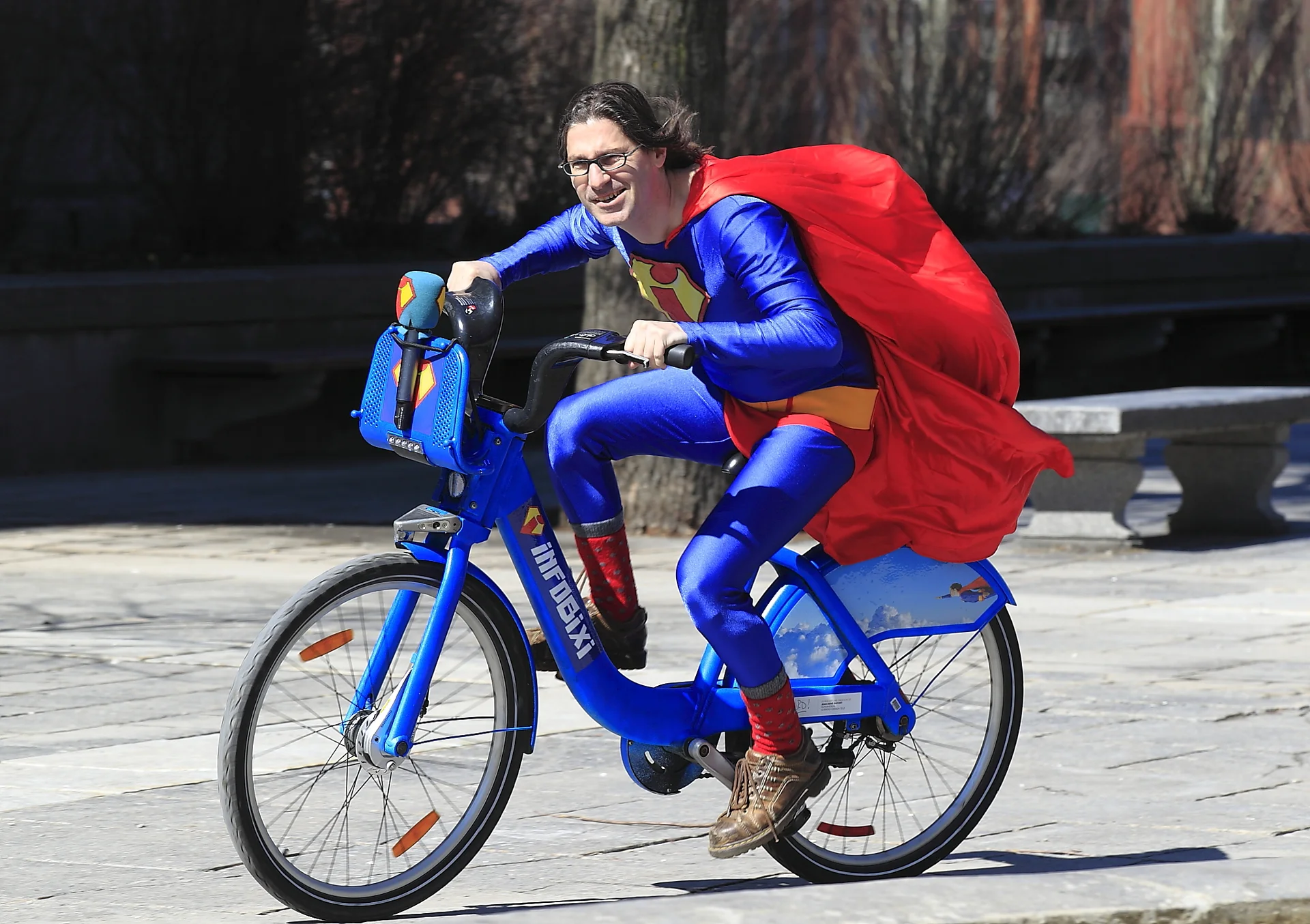 Denis Coderre riding a Bixi — Man in Superman costume rides a blue Bixi promotional bike