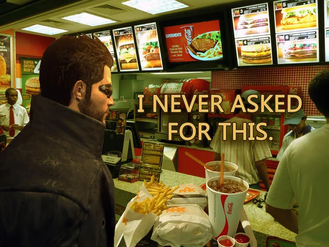 Adam Jensen standing at a fast food counter with a tray of food, captioned 'I never asked for this'