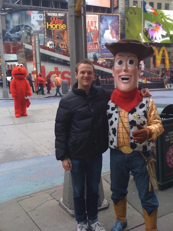 Devastated Elmo — Man posing with Woody mascot as a sad Elmo watches from behind in Times Square