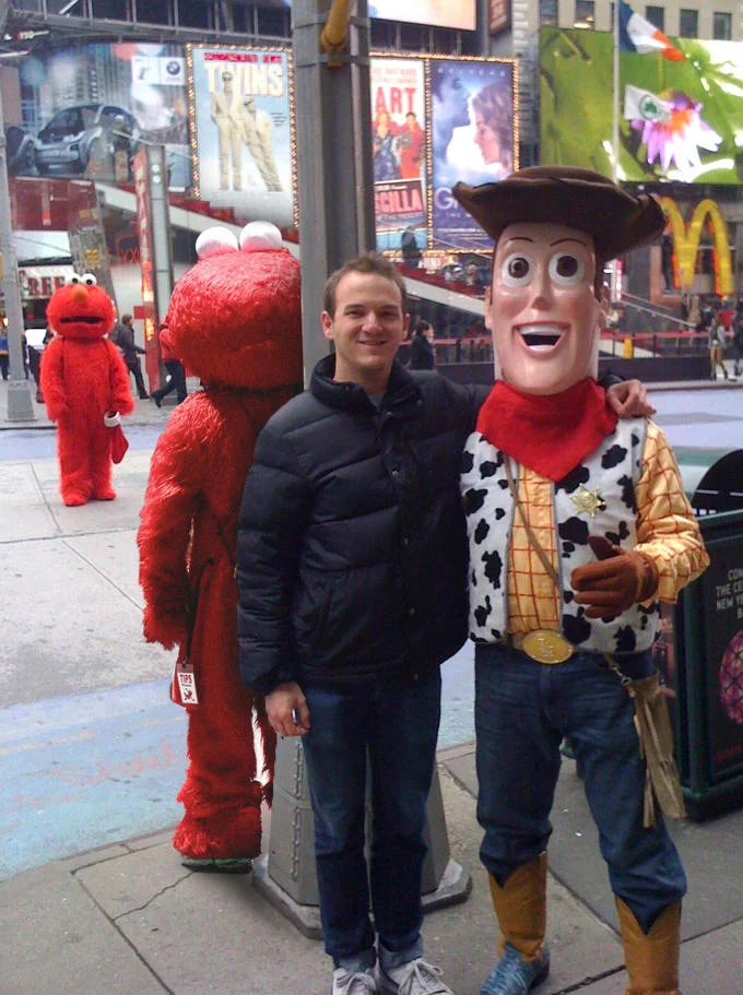 Devastated Elmo — Man posing with Woody as two sad Elmos linger behind in Times Square