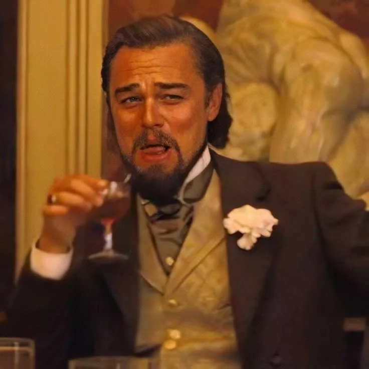Leonardo DiCaprio Laughing — Leonardo DiCaprio as Calvin Candie in Django Unchained wearing Victorian suit with boutonniere laughing while raising wine glass.