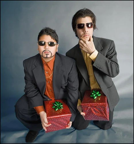 Two men in suits and sunglasses hold red gift boxes in Dick in a Box style pose