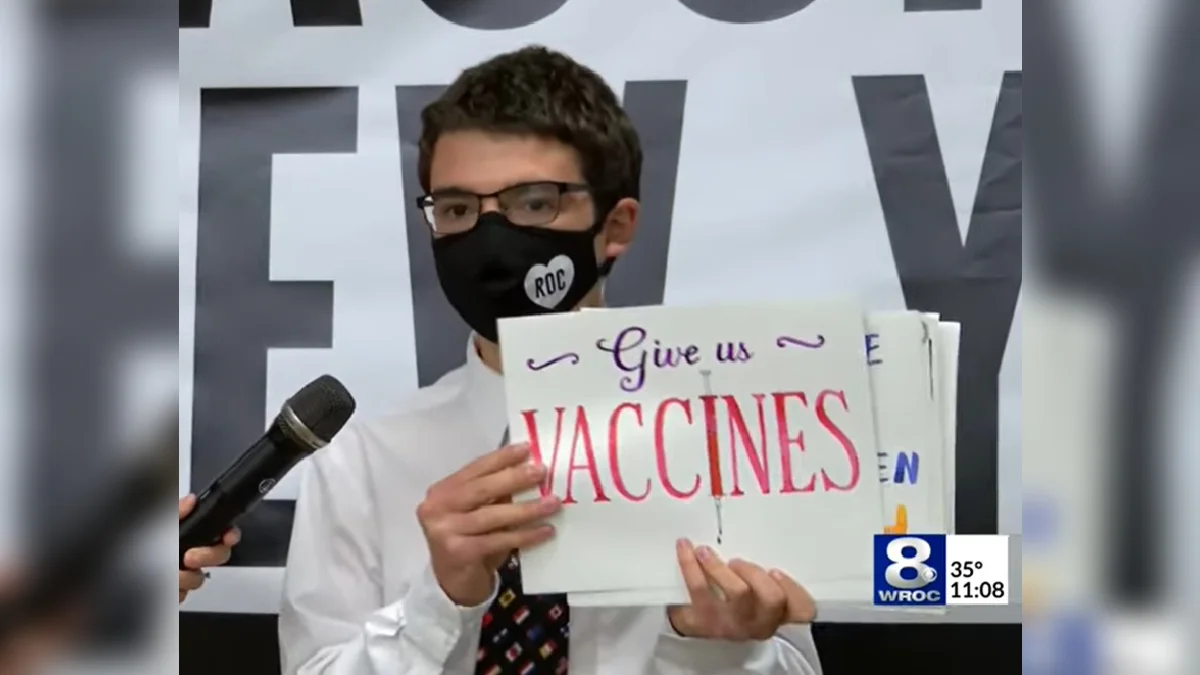 "Dr. Fauci, Give Us Vaccines" Song by Zachary Mogavero — Masked young man holds hand-lettered 'Give us VACCINES' sign on WROC Channel 8 news broadcast