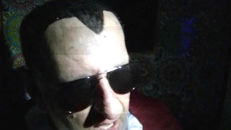 Close-up profile of Dracula Flow performer wearing white face makeup and dark sunglasses.