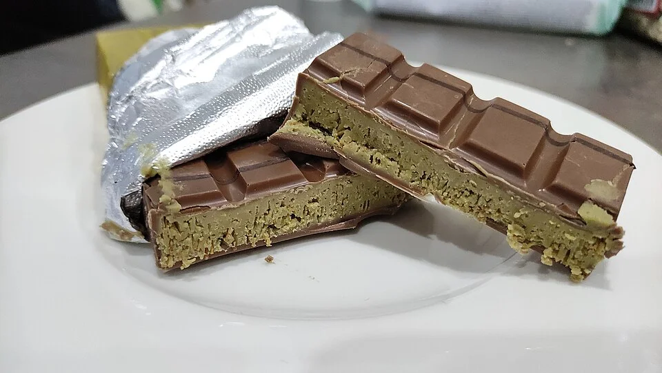 Product photograph of Dubai chocolate bar with pistachio-green filling on white plate.