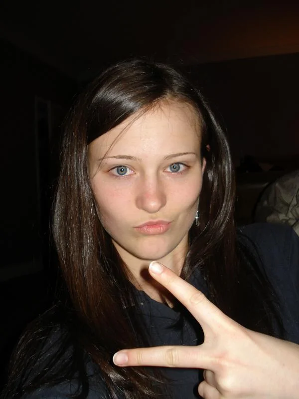 Duck Face — Brunette girl making a duck-face pose with a peace sign in a bedroom selfie