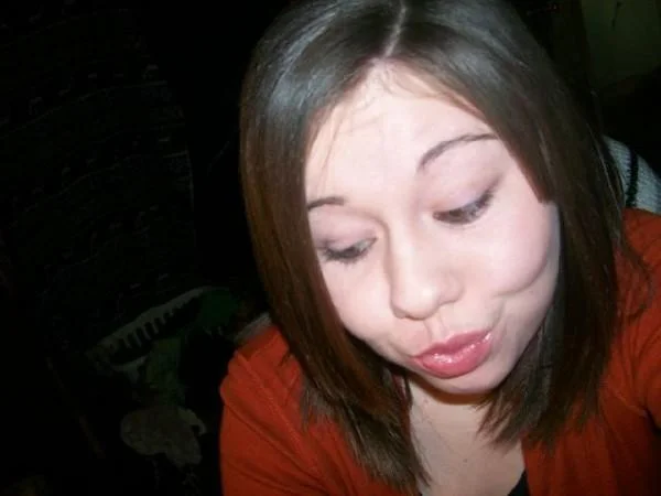 Duck Face — Brunette woman in red top making a downward-glancing duck-face selfie