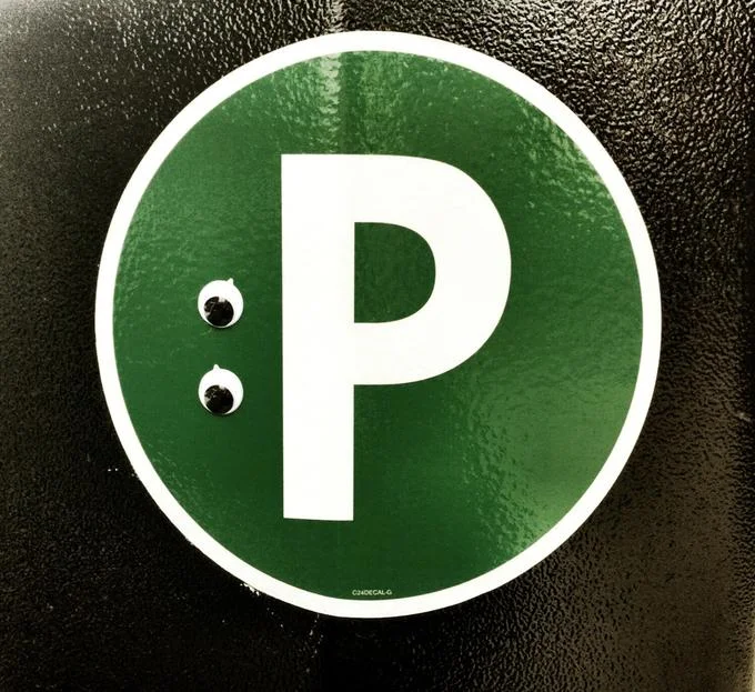 Eyebombing — Green parking sign with googly eyes attached, turning the letter P into a face