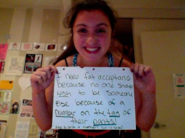 Fat Acceptance Movement — Young woman holding handwritten fat acceptance sign about pants size