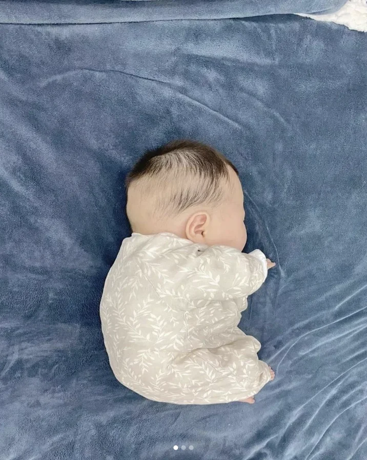 Fat Chinese Baby — Baby face-down in cream onesie on blue blanket, Instagram carousel view