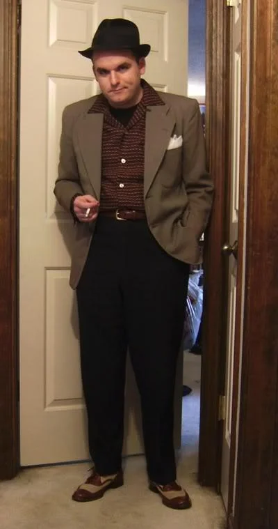 Fedora Shaming — Young man in fedora and blazer posing with cigarette in doorway