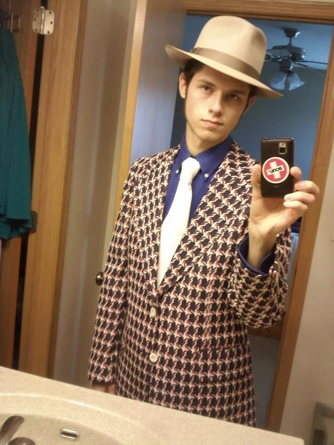 Fedora Shaming — Young man in fedora and houndstooth blazer taking a bathroom mirror selfie