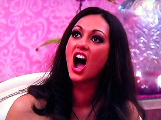 Feminist Nazi — Close-cropped photo of dark-haired woman with makeup shouting against pink background.
