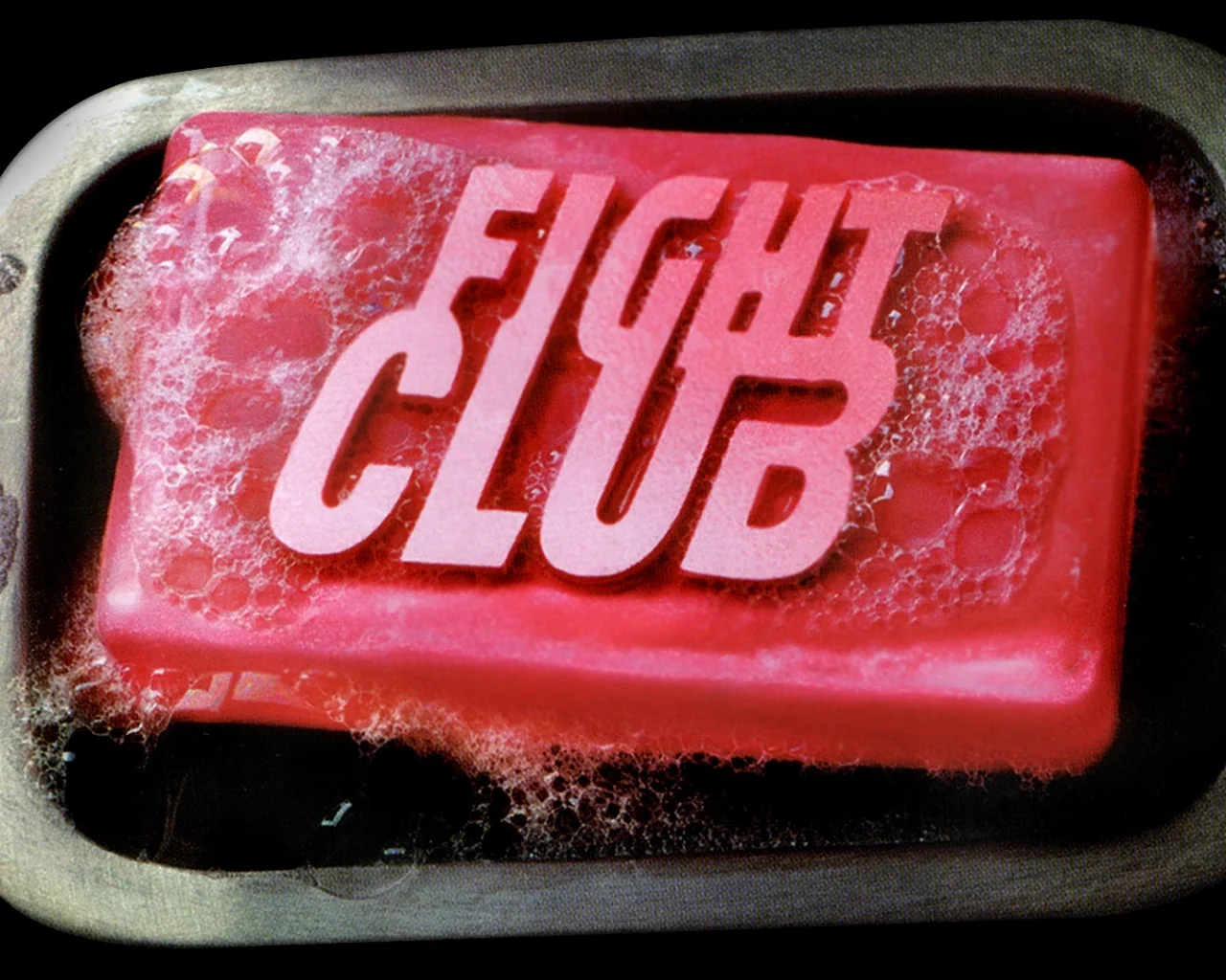 Pink soap bar with Fight Club logo embossed on top in a metal soap dish