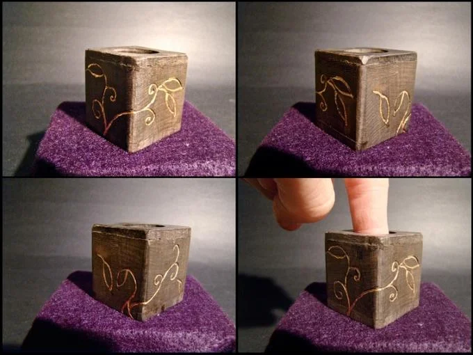 Finger Boxes — Four views of a decorated handmade wooden fingerbox with gold vine designs; finger inserted in last panel.