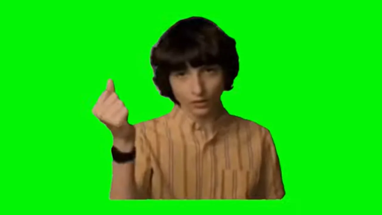 Finn Wolfhard snapping his fingers in an orange striped shirt on a green screen background
