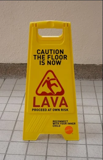 Floor Is Lava — Modified yellow caution sign reading 'CAUTION THE FLOOR IS NOW LAVA' with custom symbol.