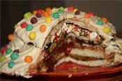 Food Porn — Frosted layer cake cut to expose colorful M&M candy and chocolate inside.