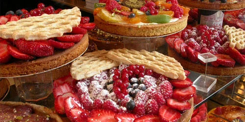 Food Porn — Bakery display case filled with ornate fruit tarts with fresh berries.