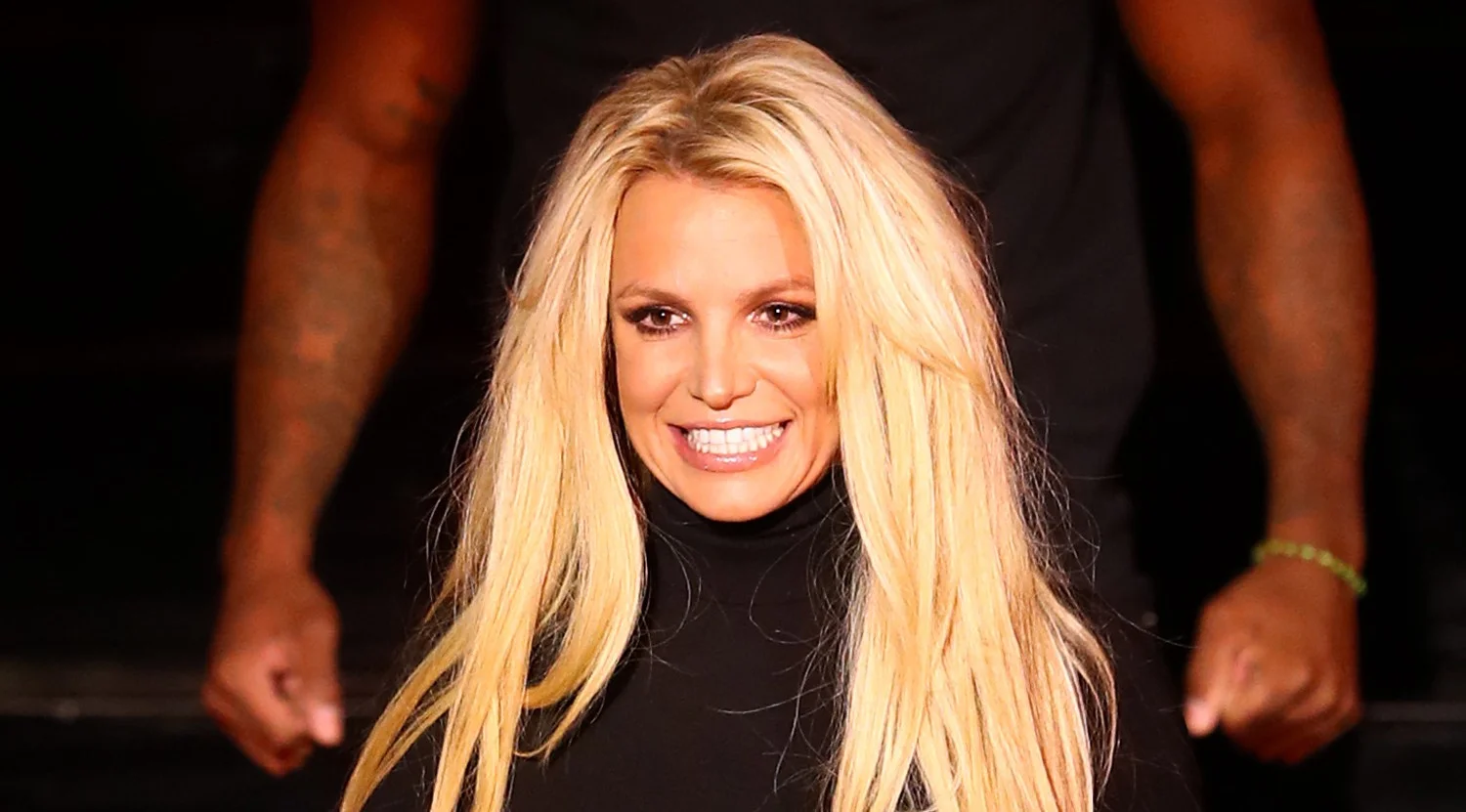 Freebritney — Britney Spears smiling in a black turtleneck with long blonde hair