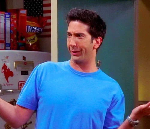 Friends — Ross Geller shrugging in a blue t-shirt with a puzzled expression