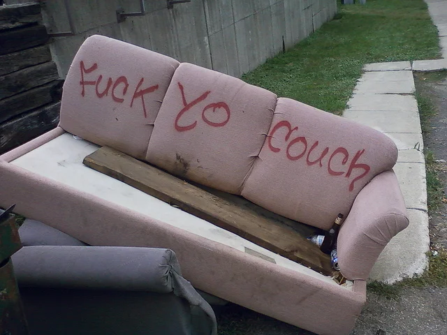 Fuck Yo Couch — Abandoned couch on a sidewalk with graffiti scrawled on the cushions