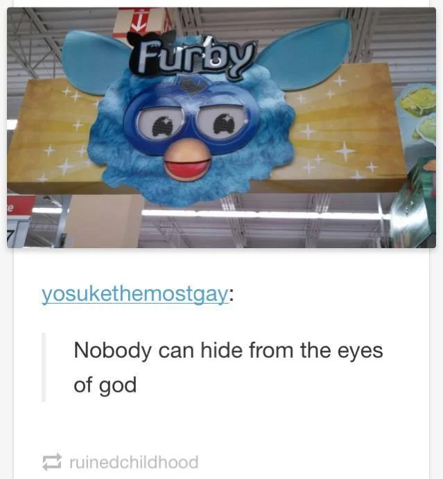 Furby toy on fire sitting on a MacBook laptop
