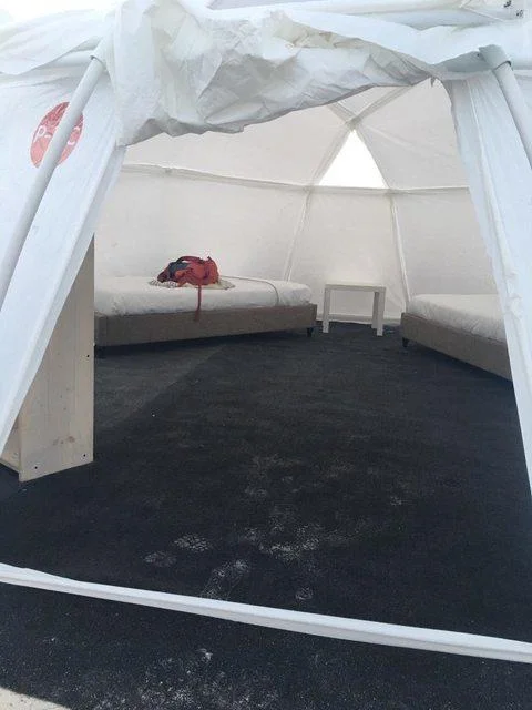 Interior of a bare Fyre Festival dome tent with two mattresses and wet floor