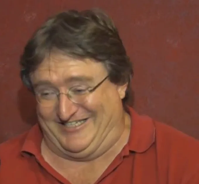 Gabe Newell laughing in a red polo shirt during an interview