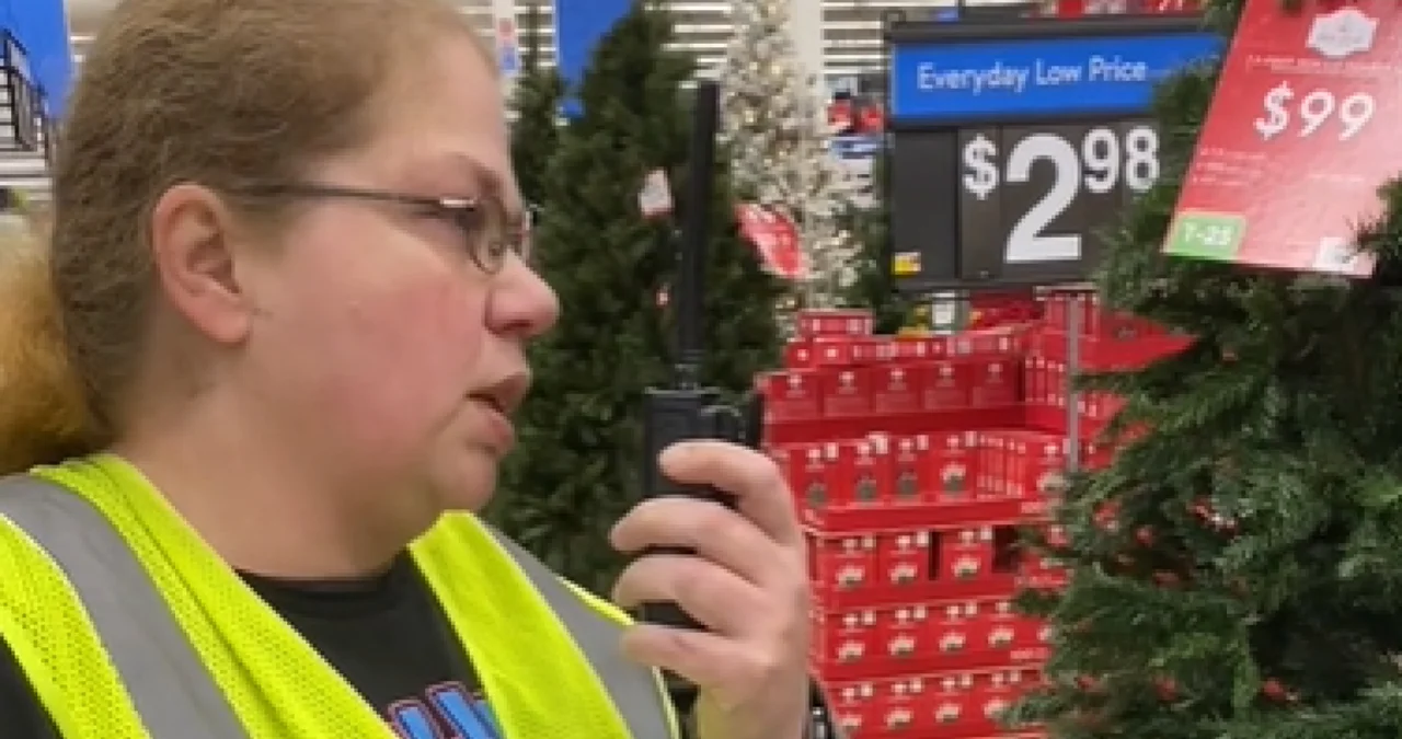 Gail Lewis, Walmart Associate, Signing Out — Walmart associate Gail Lewis in yellow safety vest holding a walkie-talkie near Christmas trees