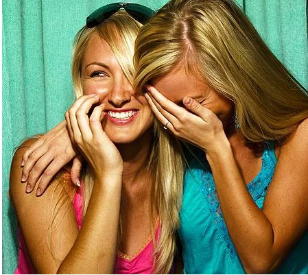 Girls Laughing — Two blonde women laughing together, one covering her face