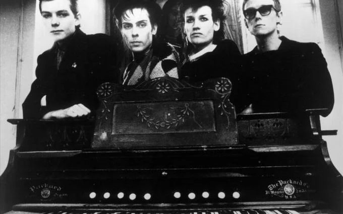 Goth — Black-and-white photo of Bauhaus band members behind an antique organ.