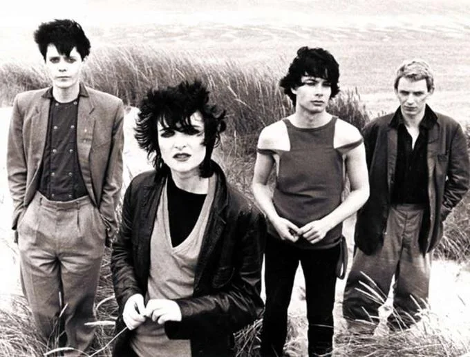 Goth — Black-and-white photo of Siouxsie and the Banshees in a windswept field.