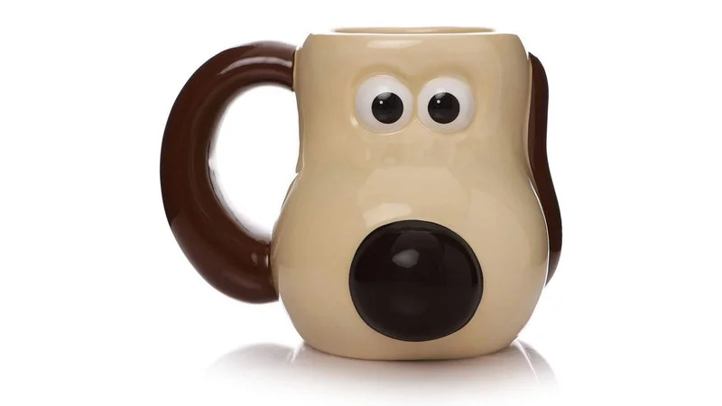 Professional product photo of cream Gromit Mug with large googly eyes and round black mouth on neutral background.
