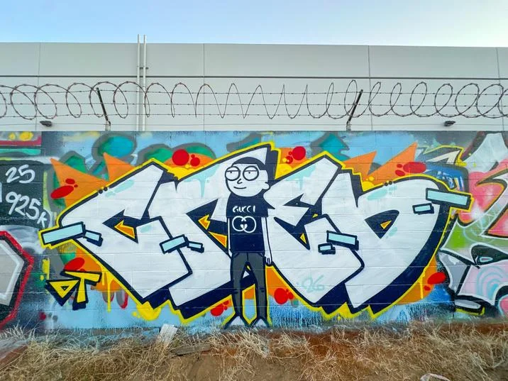 Graffiti mural on warehouse wall featuring spray-painted Gucci Morty between white bubble letters