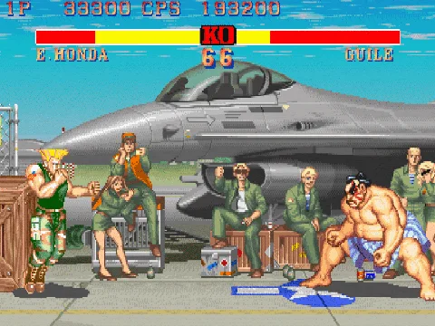 Guiles Theme Goes With Everything — Pixel-art screenshot from Street Fighter II showing Guile facing E. Honda on military airbase stage with fighter jet.