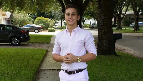Had to Do It to Em — Man in light pink shirt and white shorts posed with clasped hands on tree-lined residential sidewalk.