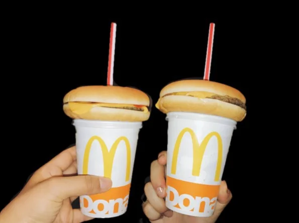 Hamburger Straws — Two McDonald's cups with cheeseburgers on top and straws through the buns against black background