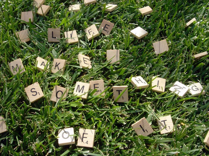 Hasbro — Scrabble tiles scattered on grass spelling out Life Make Something Of It