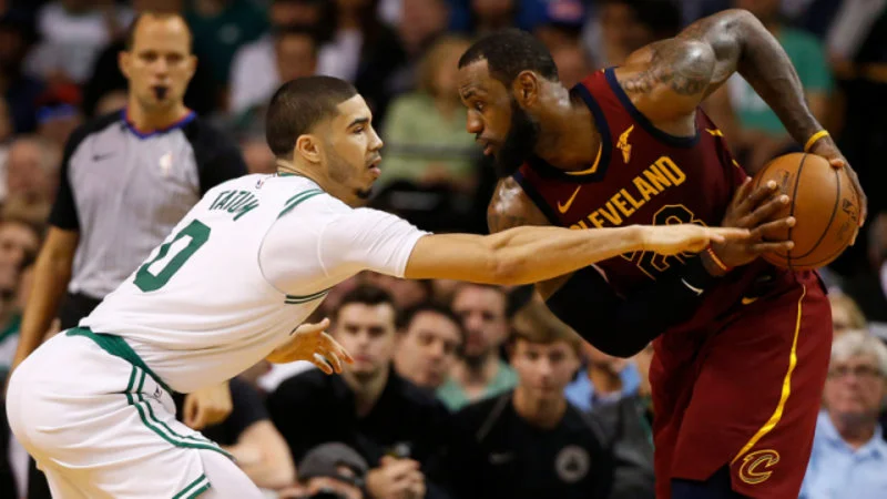 He Boomed Me — NBA basketball action photograph from a 2018 game showing a Celtics player in white and a Cavaliers player in burgundy contesting for possession.