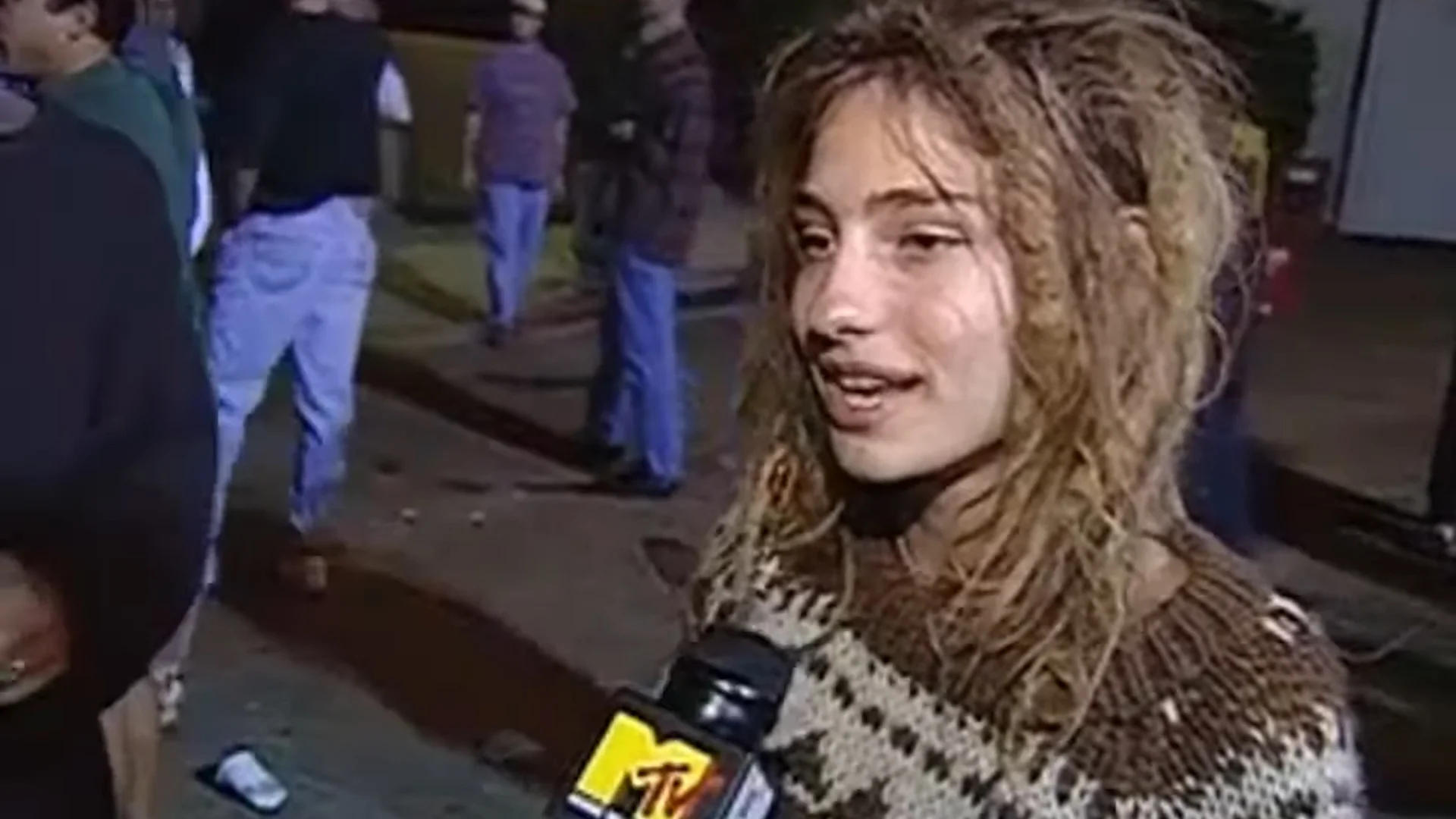 Hippie Chick Interviewed at a Phish Show — Young woman with wavy brown hair being interviewed with an MTV microphone outside a Phish show at night.