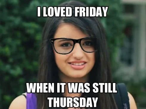 Smiling woman with long dark hair wearing black thick-framed hipster glasses against green foliage with mainstream caption.