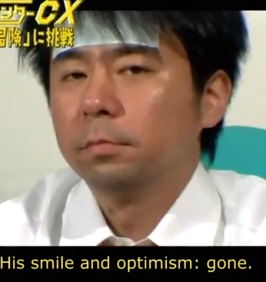 Shinya Arino from Game Center CX with blank expression and subtitle reading 'His smile and optimism: gone.'