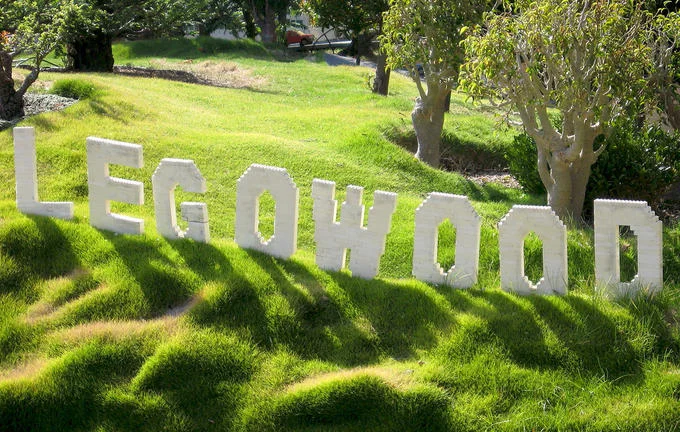 Hollywood Sign Parodies — LEGOWOOD sign built from white LEGO bricks on a grassy hill at Legoland