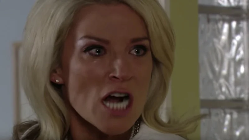 How Long — Clean screenshot of Vanessa from EastEnders with wide eyes and open mouth conveying shock and urgent demand.