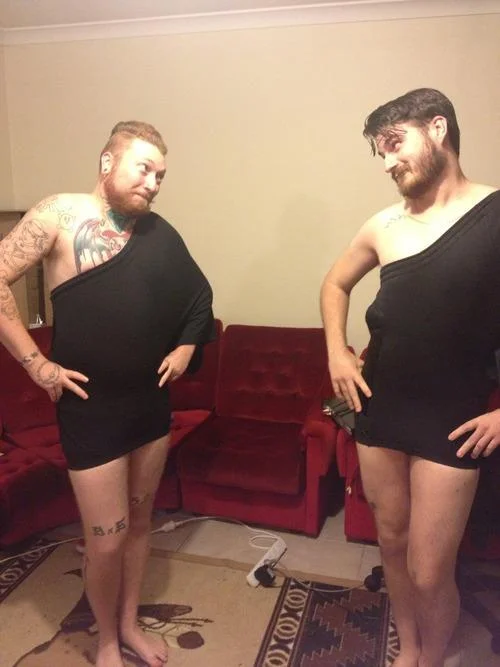 How To Make A Cute Dress Out Of Shorts — Two men sit on red couch each wearing black shorts as one-sleeved dress.