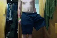 How To Make A Cute Dress Out Of Shorts — Shirtless person wears navy shorts with one arm through leg opening as dress.