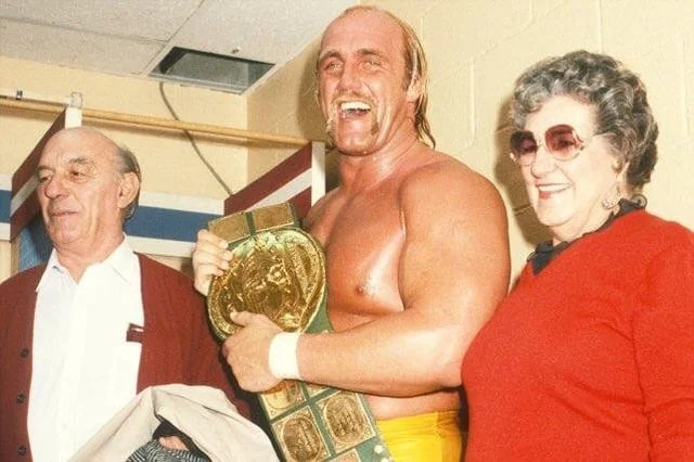 Young Hulk Hogan in red pants at a Japanese storefront speaking with another man